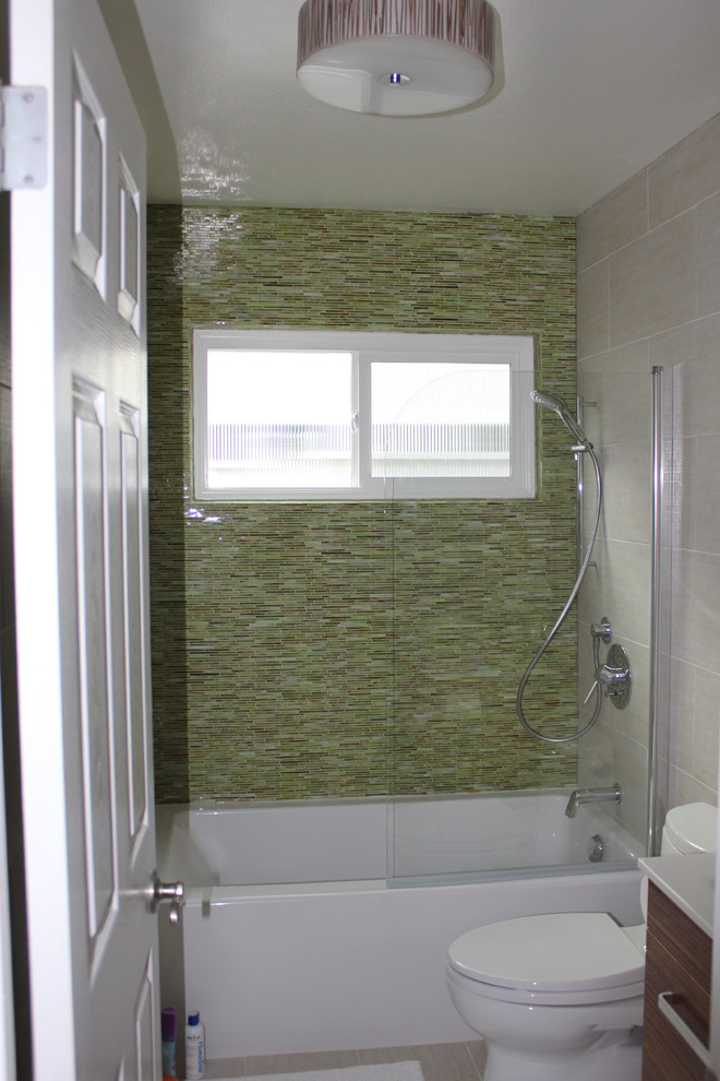 Photo of a medium sized coastal family bathroom in Orange County with a shower/bath combination, flat-panel cabinets, dark wood cabinets, an alcove bath, a two-piece toilet, green tiles, matchstick tiles, beige walls, a vessel sink, solid surface worktops and an open shower.