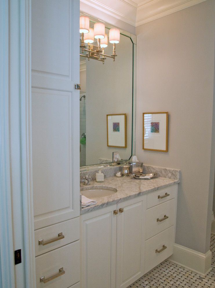 Modelo de cuarto de baño clásico con lavabo bajoencimera, armarios con paneles con relieve, puertas de armario blancas y encimera de granito