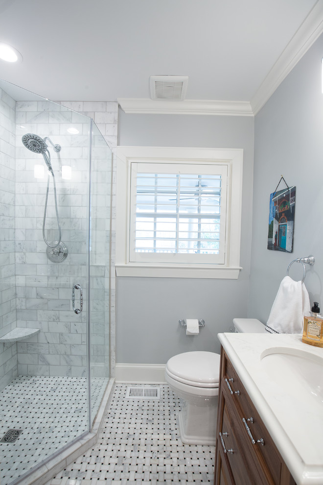 Example of a small transitional 3/4 gray tile and marble tile marble floor and white floor corner shower design in Charlotte with raised-panel cabinets, medium tone wood cabinets, a one-piece toilet, gray walls, an integrated sink, quartzite countertops and a hinged shower door