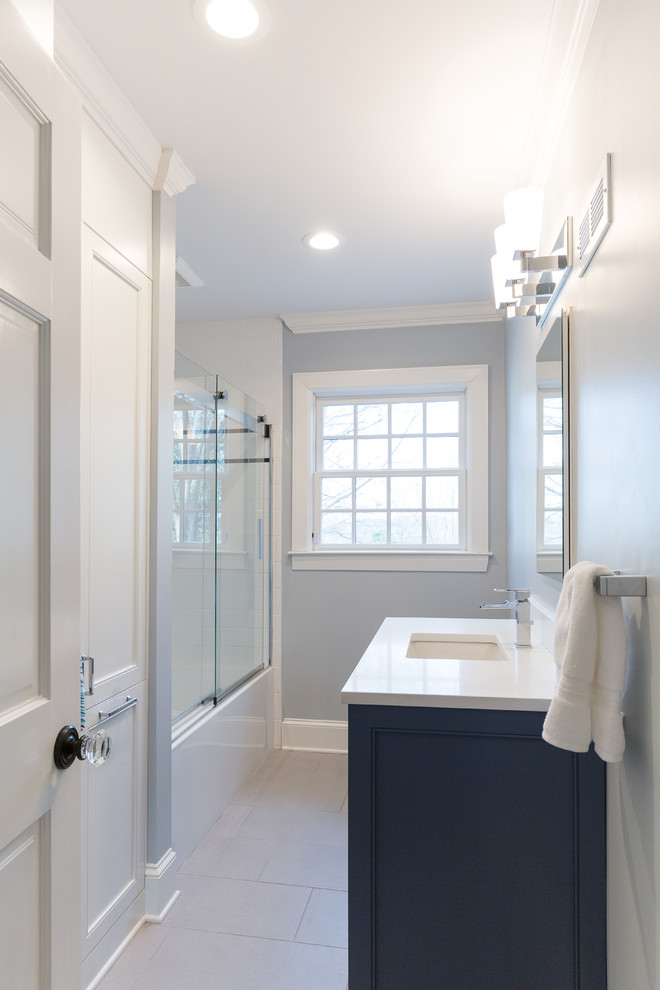 Corner shower - small transitional 3/4 gray tile and marble tile marble floor and white floor corner shower idea in Charlotte with raised-panel cabinets, medium tone wood cabinets, a one-piece toilet, gray walls, an integrated sink, quartzite countertops and a hinged shower door