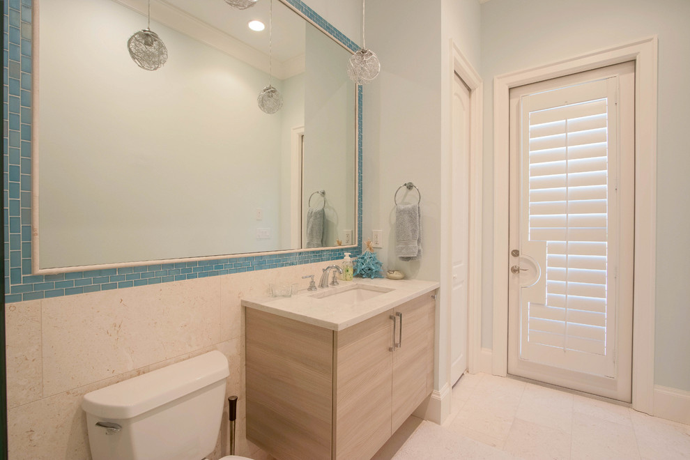 Idées déco pour une salle de bain contemporaine en bois clair de taille moyenne avec un placard à porte plane, une douche d'angle, WC séparés, un carrelage beige, un carrelage de pierre, un mur bleu, un lavabo encastré, un plan de toilette en granite, un sol beige et une cabine de douche à porte battante.