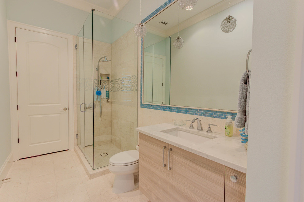 Inredning av ett modernt mellanstort badrum, med släta luckor, skåp i ljust trä, en hörndusch, en toalettstol med separat cisternkåpa, beige kakel, stenkakel, blå väggar, ett undermonterad handfat, granitbänkskiva, beiget golv och dusch med gångjärnsdörr