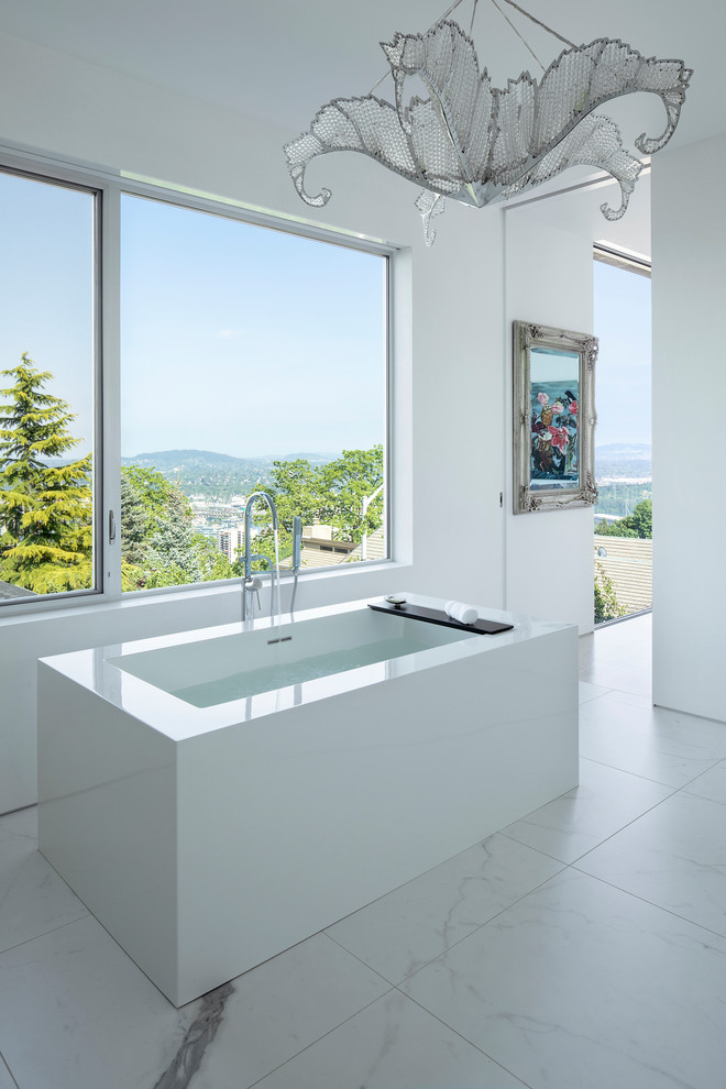 На фото: ванная комната в стиле модернизм с отдельно стоящей ванной, белыми стенами и белым полом с