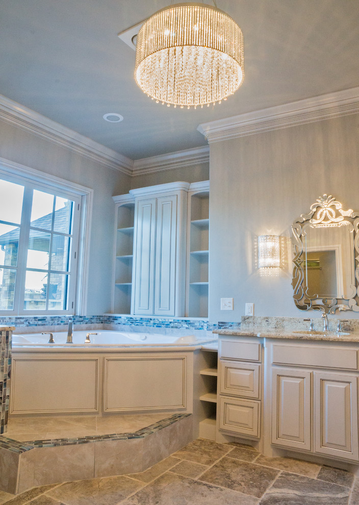 Идея дизайна: огромная главная ванная комната в классическом стиле с стеклянными фасадами, белыми фасадами, угловой ванной, синей плиткой, стеклянной плиткой, бежевыми стенами, полом из сланца, монолитной раковиной и столешницей из гранита