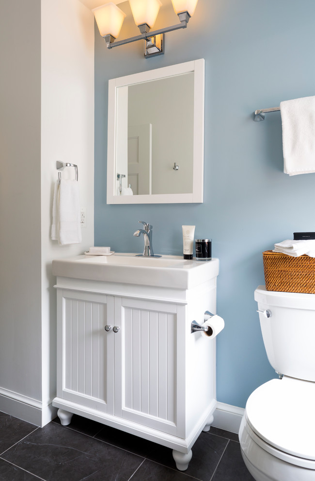 Photo of a small family bathroom in DC Metro with white cabinets, an alcove bath, a shower/bath combination, a two-piece toilet, grey tiles, porcelain tiles, blue walls, porcelain flooring, an integrated sink and recessed-panel cabinets.