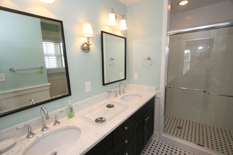 Inredning av ett maritimt mellanstort en-suite badrum, med ett nedsänkt handfat, luckor med infälld panel, svarta skåp, marmorbänkskiva, en kantlös dusch, svart och vit kakel, blå väggar, tunnelbanekakel och klinkergolv i porslin
