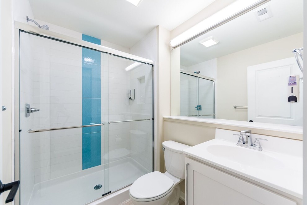 Idéer för att renovera ett litet maritimt badrum med dusch, med skåp i shakerstil, vita skåp, en dusch i en alkov, en toalettstol med separat cisternkåpa, blå kakel, vit kakel, keramikplattor, beige väggar, vinylgolv, ett integrerad handfat, bänkskiva i akrylsten, brunt golv och dusch med skjutdörr
