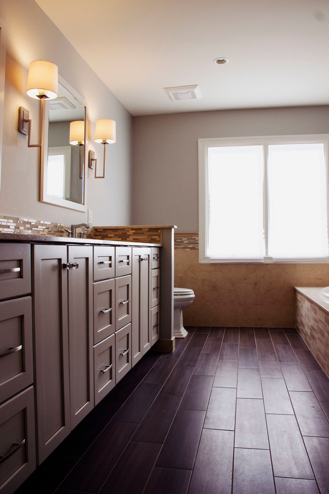 Modelo de cuarto de baño tradicional renovado con lavabo bajoencimera, bañera encastrada sin remate, combinación de ducha y bañera, sanitario de una pieza, paredes beige y suelo de baldosas de porcelana