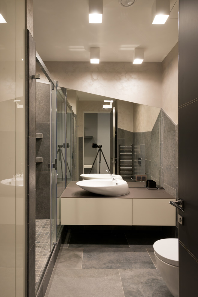 Diseño de cuarto de baño actual con lavabo sobreencimera, armarios con paneles lisos, puertas de armario blancas, ducha empotrada, baldosas y/o azulejos grises, paredes grises y encimeras grises