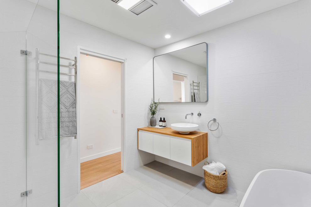 Exemple d'une grande salle de bain moderne en bois clair avec une baignoire indépendante, un carrelage gris, un mur blanc, carreaux de ciment au sol, une vasque, un plan de toilette en bois, un sol blanc, un plan de toilette marron, meuble simple vasque et meuble-lavabo suspendu.