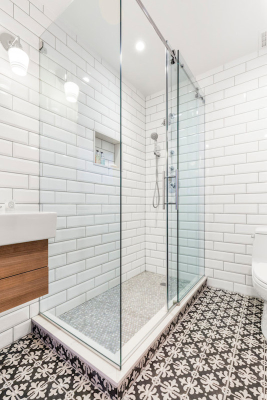 Inspiration for a mid-sized transitional 3/4 white tile and subway tile multicolored floor corner shower remodel in New York with flat-panel cabinets, medium tone wood cabinets, a one-piece toilet, pink walls, an integrated sink and a hinged shower door
