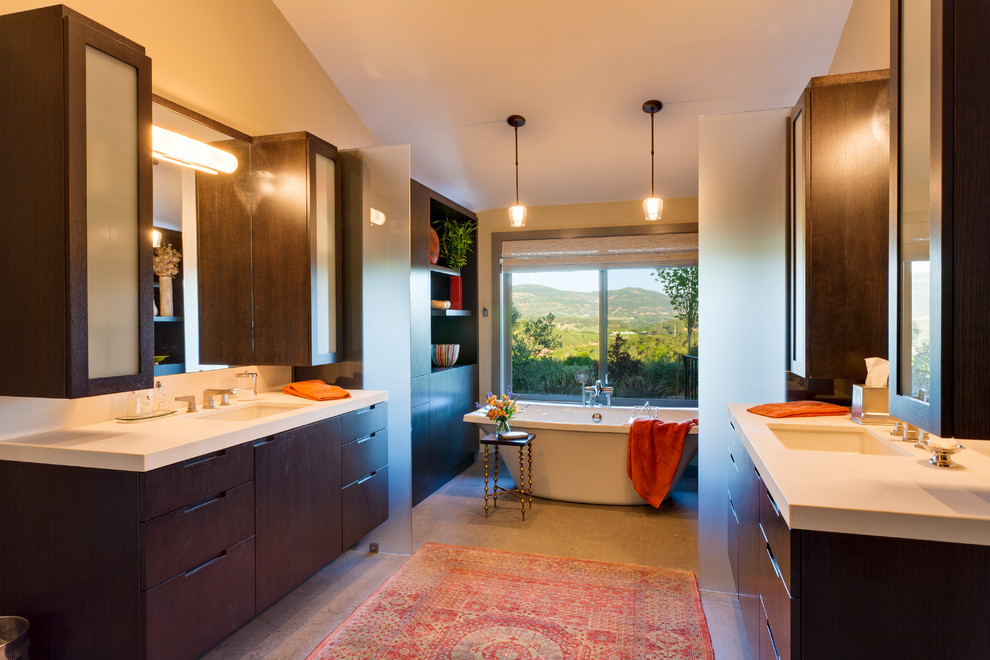 Exempel på ett mellanstort modernt badrum, med ett undermonterad handfat, möbel-liknande, skåp i mörkt trä, bänkskiva i kalksten, ett fristående badkar, en dusch i en alkov, en toalettstol med hel cisternkåpa, grå kakel, stenhäll, grå väggar och kalkstensgolv
