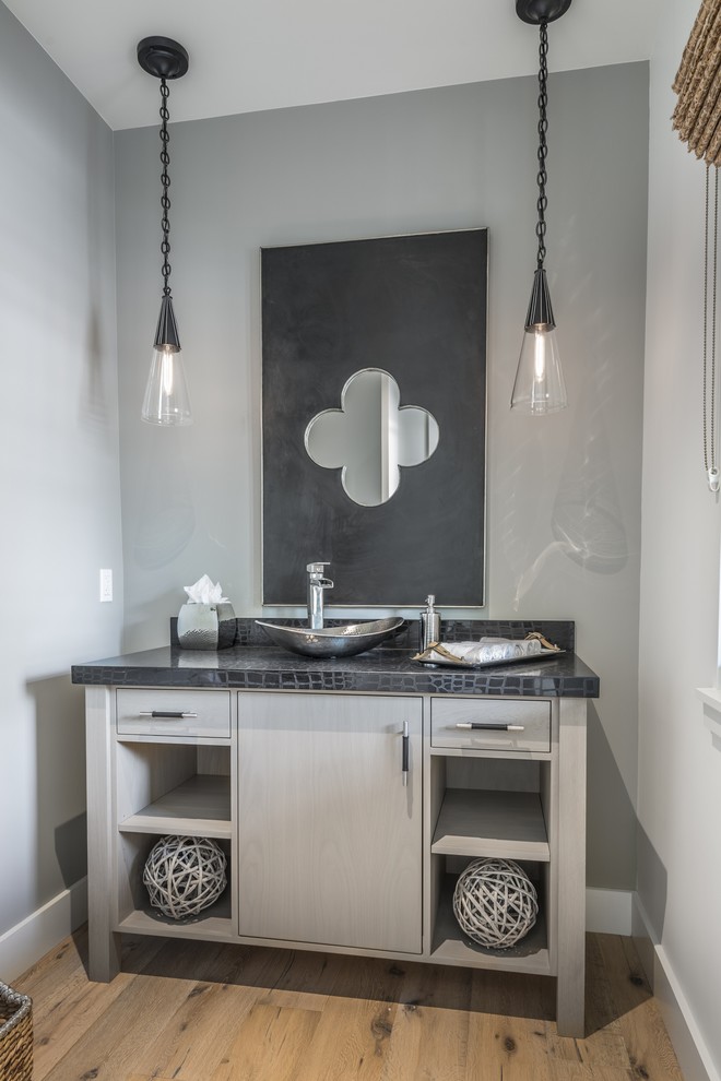 Bild på ett mellanstort funkis badrum med dusch, med släta luckor, grå skåp, en toalettstol med hel cisternkåpa, grå väggar, ljust trägolv, ett fristående handfat och kaklad bänkskiva