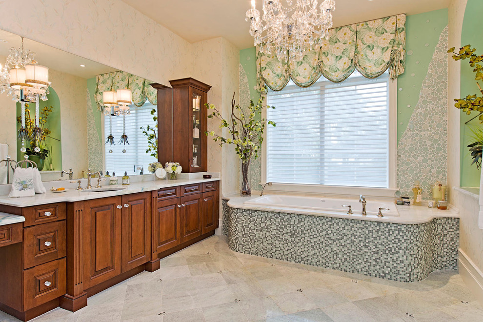 Immagine di una stanza da bagno tropicale con vasca da incasso, piastrelle a mosaico, ante con bugna sagomata e ante in legno scuro