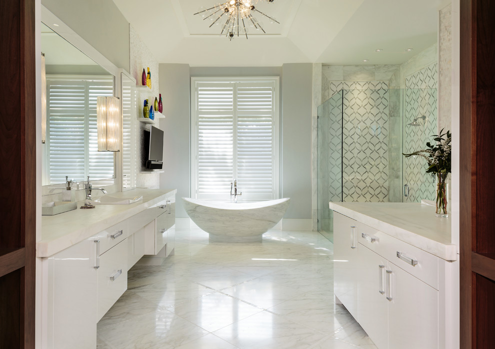 Inredning av ett modernt stort vit vitt en-suite badrum, med släta luckor, vita skåp, ett fristående badkar, en hörndusch, marmorgolv, marmorbänkskiva, vitt golv, dusch med gångjärnsdörr, grå kakel, vit kakel, grå väggar och ett fristående handfat