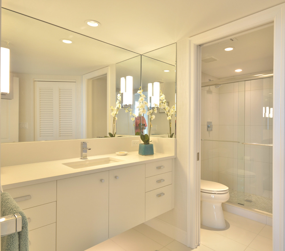 Inspiration for a mid-sized coastal master white tile and ceramic tile ceramic tile and white floor bathroom remodel in Miami with an undermount sink, flat-panel cabinets, white cabinets, quartzite countertops, a two-piece toilet and white walls