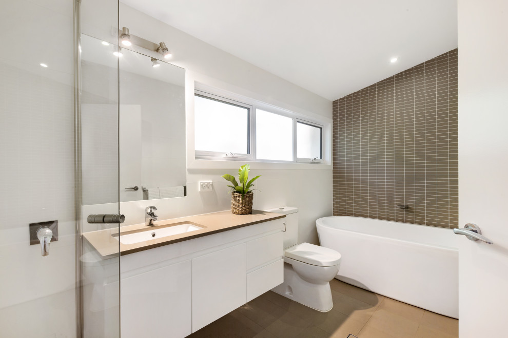Idéer för att renovera ett stort funkis beige beige en-suite badrum, med ett fristående badkar, vita väggar, klinkergolv i porslin, bänkskiva i kvartsit, beiget golv, släta luckor, vita skåp, brun kakel och ett undermonterad handfat