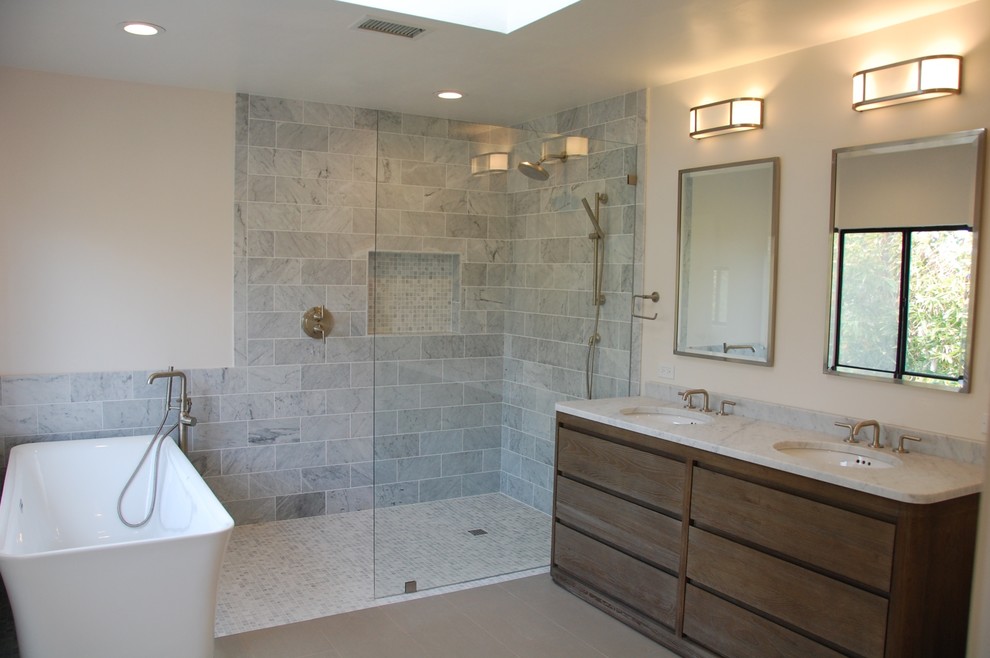 Inspiration for a medium sized contemporary ensuite bathroom in San Diego with flat-panel cabinets, dark wood cabinets, a freestanding bath, a walk-in shower, grey tiles, marble tiles, beige walls, a submerged sink, granite worktops, an open shower and grey worktops.