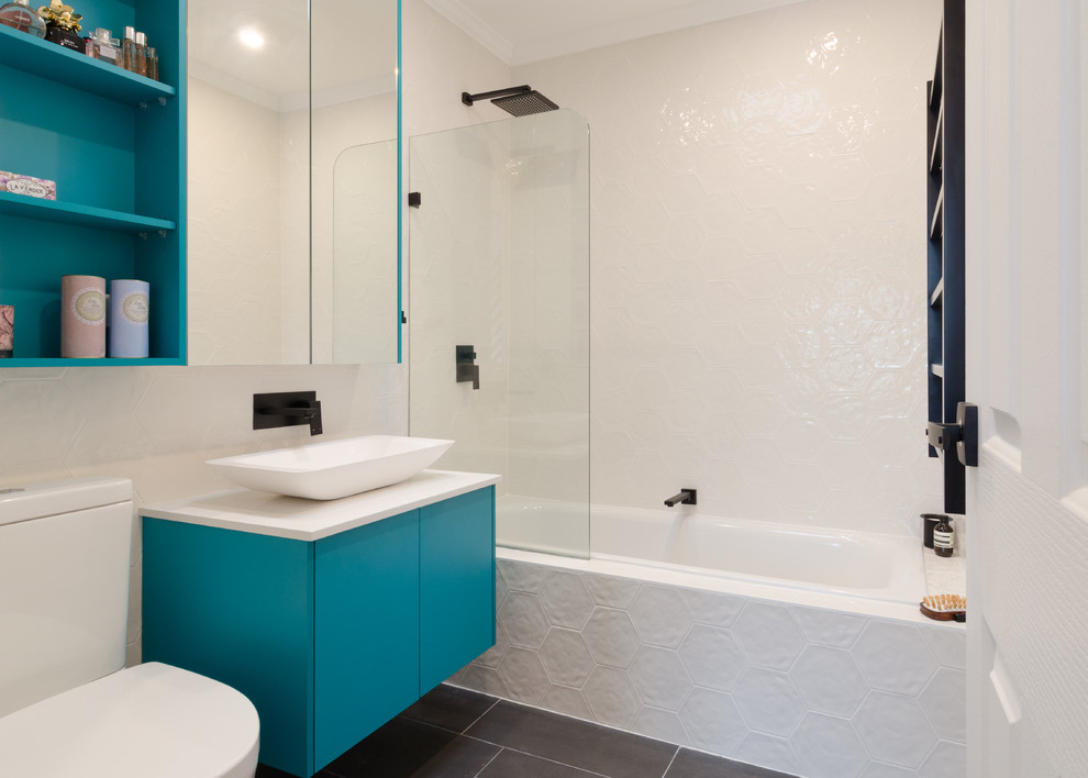 Idéer för ett litet modernt en-suite badrum, med släta luckor, gröna skåp, ett platsbyggt badkar, en dusch/badkar-kombination, en toalettstol med hel cisternkåpa, grå kakel, keramikplattor, vita väggar, klinkergolv i keramik, ett avlångt handfat och bänkskiva i kvarts