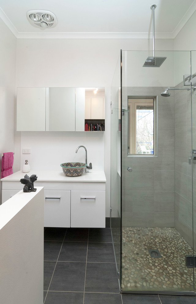 Ejemplo de cuarto de baño actual con lavabo sobreencimera, armarios con paneles lisos, puertas de armario blancas, ducha esquinera, baldosas y/o azulejos grises y paredes blancas