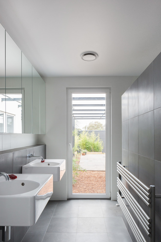 Cette image montre une salle de bain design avec un lavabo suspendu, un carrelage gris et un mur blanc.