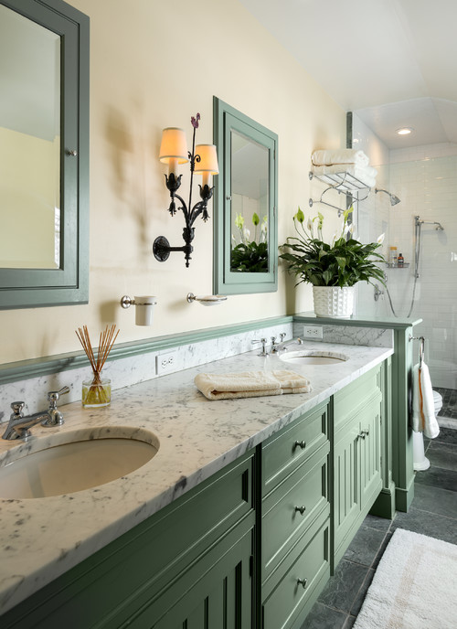 Traditional bathroom with green vanity cabinets, marble countertop, and double sinks