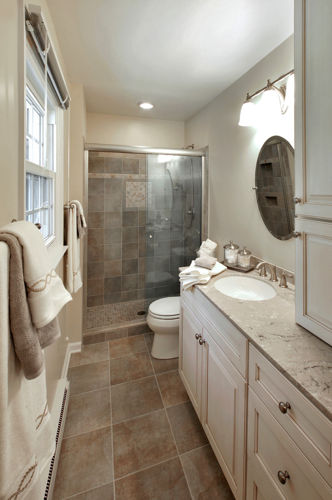 Idéer för mellanstora vintage badrum med dusch, med luckor med upphöjd panel, vita skåp, en toalettstol med separat cisternkåpa, brun kakel, porslinskakel, beige väggar, en dusch i en alkov, klinkergolv i keramik, ett undermonterad handfat, bänkskiva i kalksten, brunt golv och dusch med skjutdörr