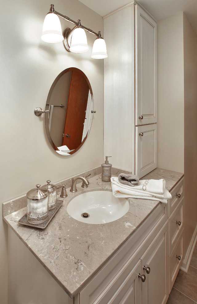 Klassisk inredning av ett mellanstort badrum med dusch, med luckor med upphöjd panel, vita skåp, en toalettstol med separat cisternkåpa, brun kakel, porslinskakel, beige väggar, en dusch i en alkov, klinkergolv i keramik, ett undermonterad handfat, bänkskiva i kalksten, brunt golv och dusch med skjutdörr