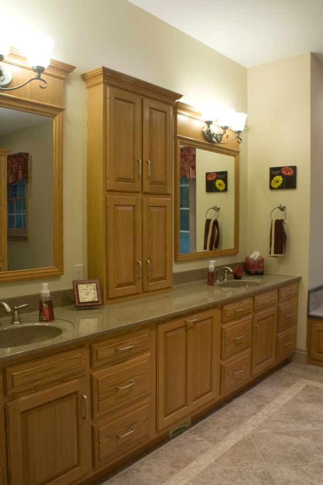 This is an example of a large traditional ensuite bathroom in Philadelphia with raised-panel cabinets, medium wood cabinets, a built-in bath, an alcove shower, a two-piece toilet, beige tiles, porcelain tiles, beige walls, porcelain flooring, an integrated sink and marble worktops.