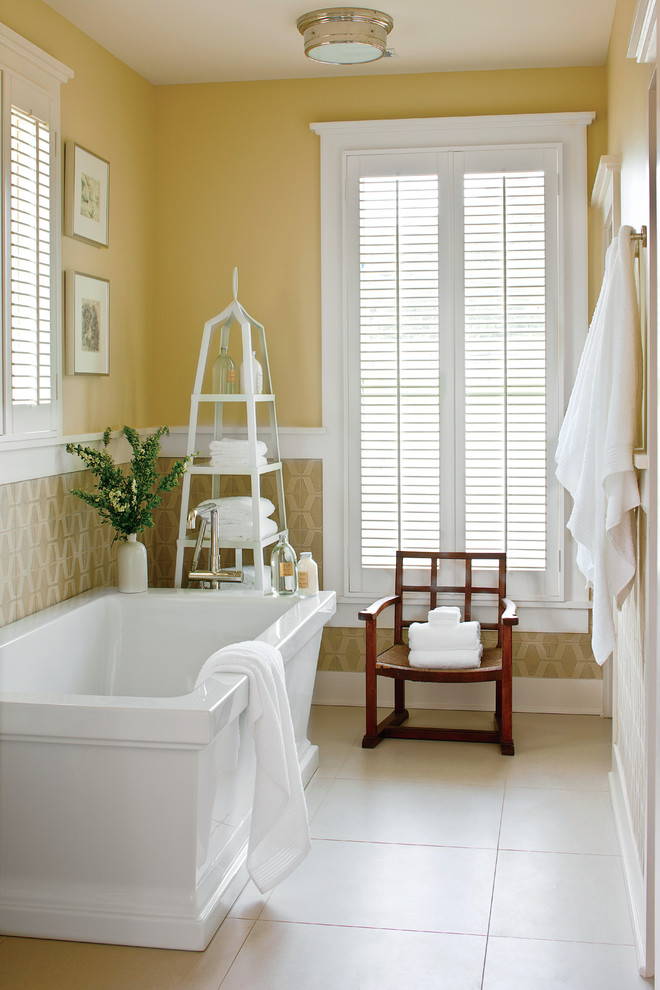 На фото: главная ванная комната в классическом стиле с отдельно стоящей ванной, желтыми стенами и окном с