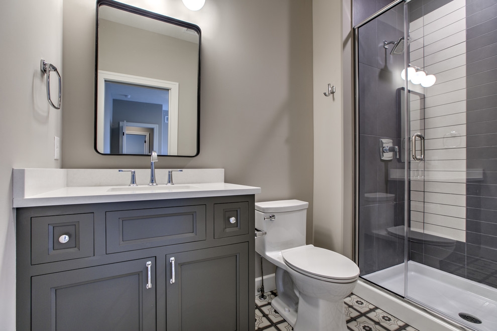 Idées déco pour une salle de bain campagne de taille moyenne avec un placard avec porte à panneau encastré, des portes de placard grises, WC à poser, un carrelage bleu, des carreaux de porcelaine, un mur gris, un sol en carrelage de porcelaine, un lavabo encastré, un plan de toilette en quartz modifié, un sol multicolore, une cabine de douche à porte coulissante et un plan de toilette blanc.
