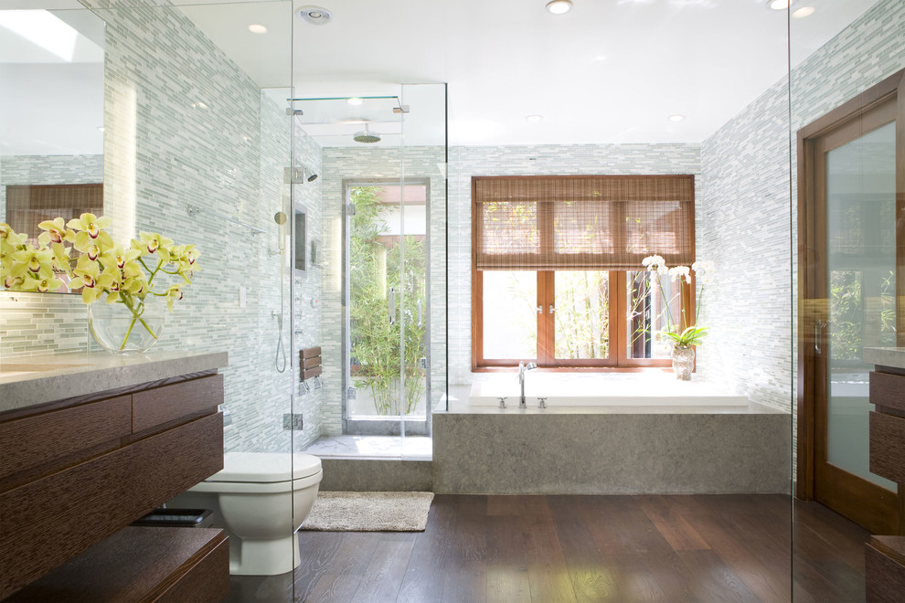 Foto di una stanza da bagno minimal con ante lisce, ante in legno bruno, vasca da incasso, doccia ad angolo, piastrelle grigie e piastrelle a listelli