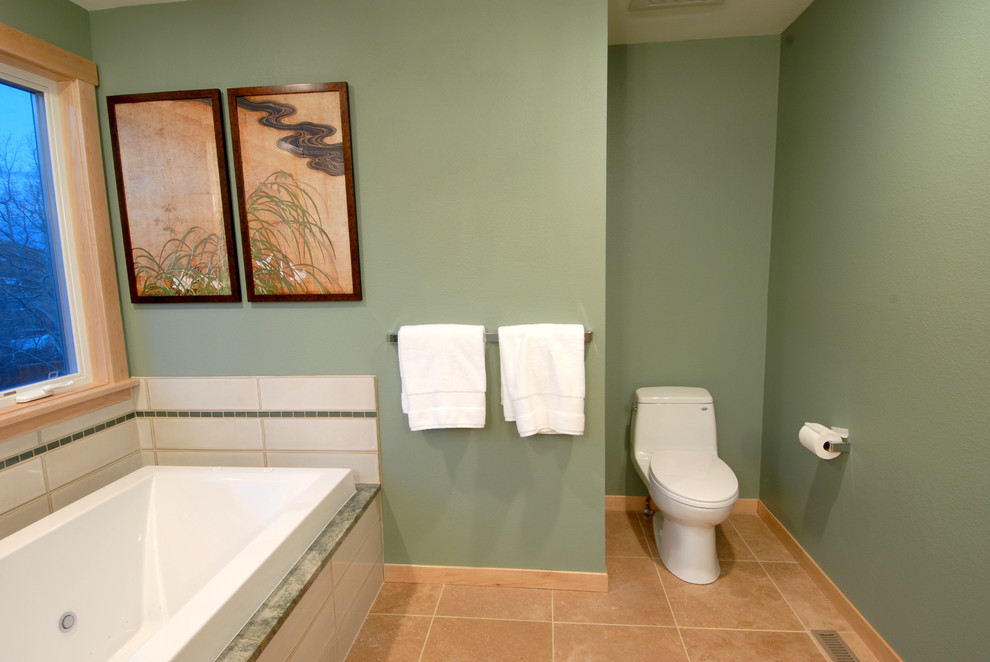 Modelo de cuarto de baño contemporáneo con lavabo sobreencimera, armarios con paneles lisos, puertas de armario de madera clara, encimera de granito, bañera encastrada, ducha esquinera, sanitario de una pieza, baldosas y/o azulejos verdes y baldosas y/o azulejos de vidrio