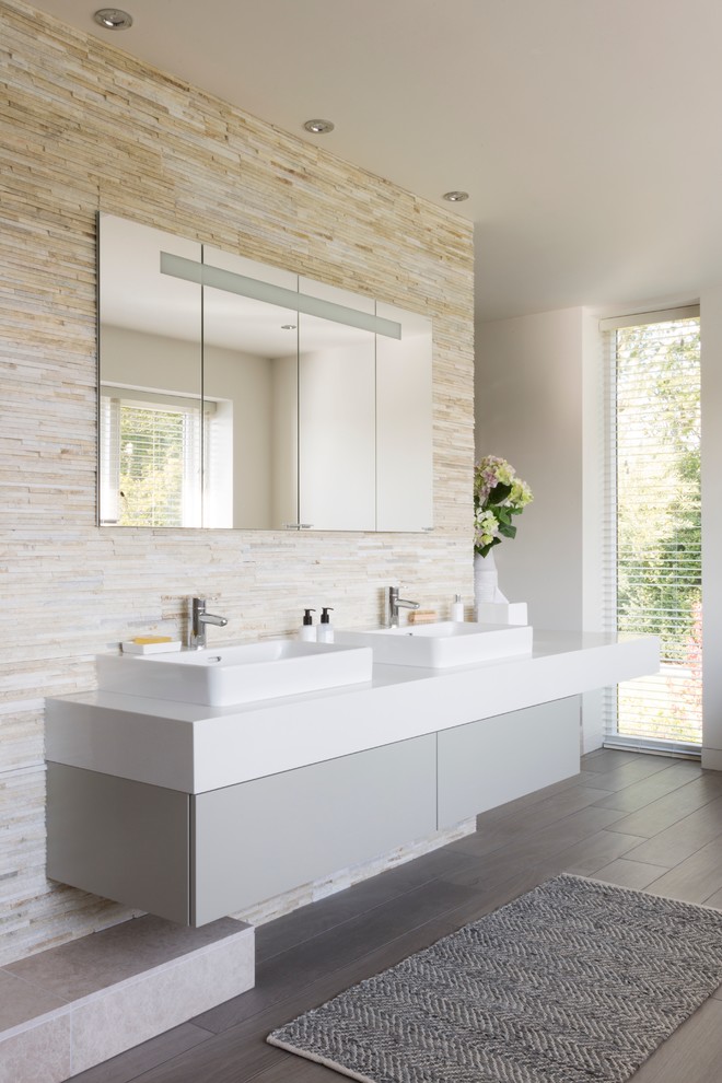 Пример оригинального дизайна: главная ванная комната в современном стиле с плоскими фасадами, серыми фасадами, белыми стенами, темным паркетным полом и настольной раковиной