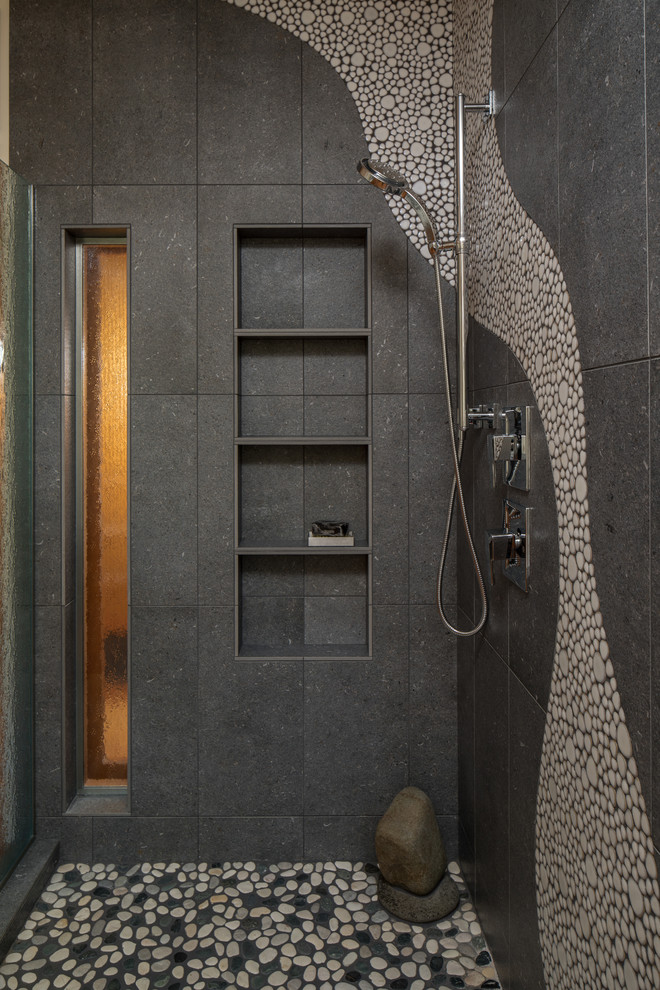 Bild på ett stort funkis grå grått badrum, med skåp i mellenmörkt trä, ett platsbyggt badkar, en toalettstol med hel cisternkåpa, flerfärgad kakel, kakel i småsten, ett nedsänkt handfat, bänkskiva i betong och dusch med gångjärnsdörr