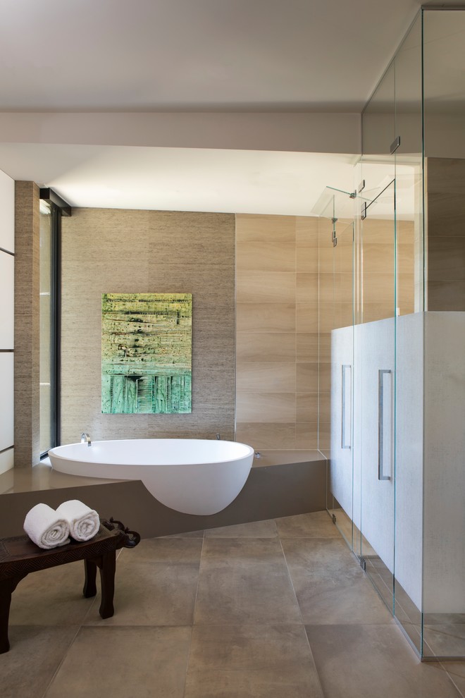 Example of a large trendy master limestone floor and beige floor drop-in bathtub design in Phoenix with light wood cabinets, brown walls, a drop-in sink, marble countertops and a hinged shower door