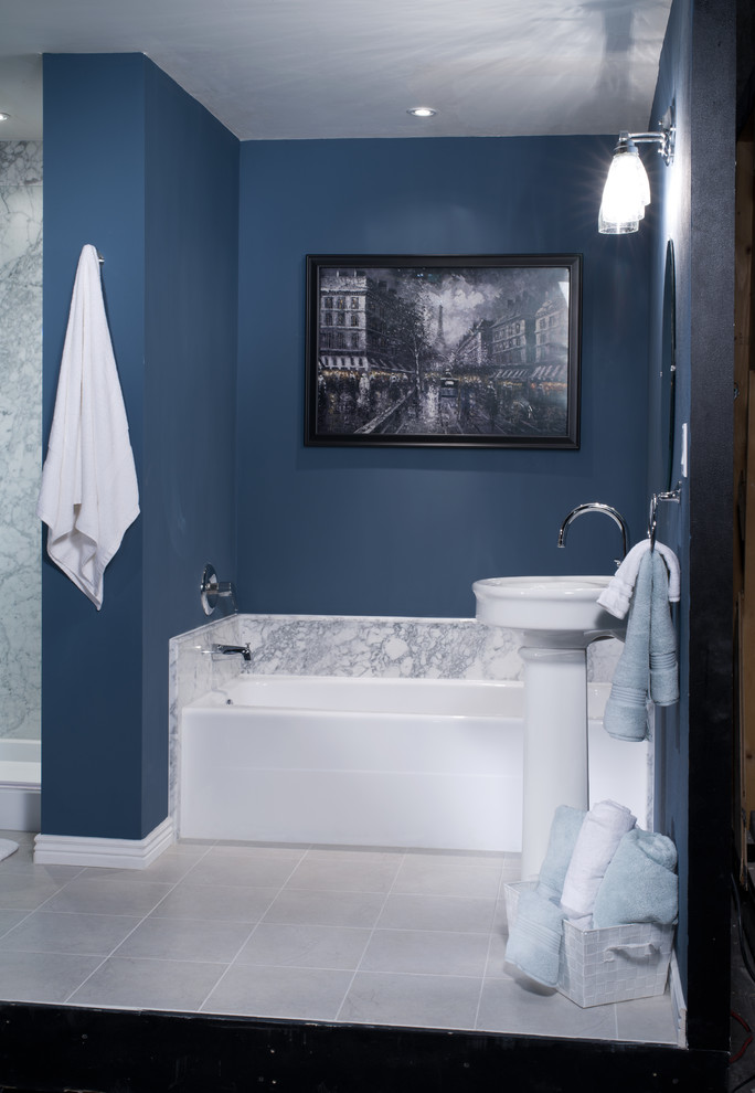 Ispirazione per una stanza da bagno padronale minimalista di medie dimensioni con lavabo a colonna, vasca ad alcova, piastrelle bianche, piastrelle in pietra e pareti blu