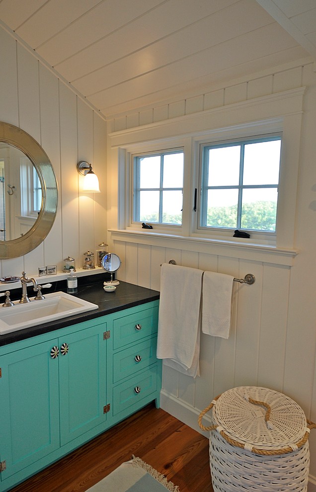 Modelo de cuarto de baño costero con puertas de armario verdes, paredes blancas, suelo de madera en tonos medios y encimera de esteatita