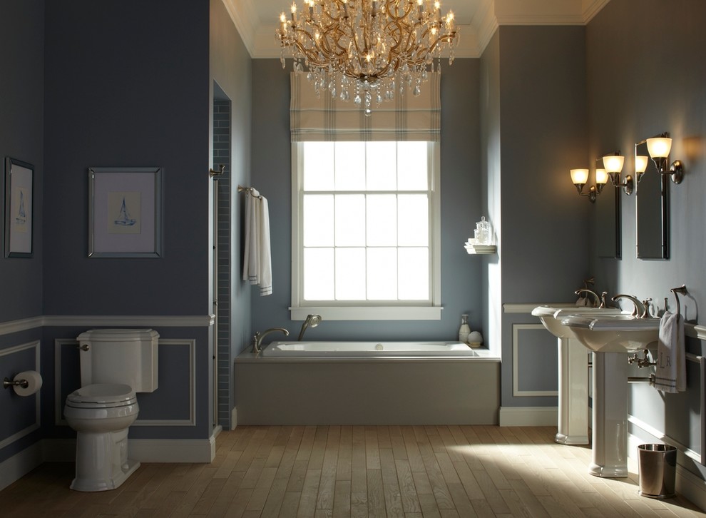 На фото: главная ванная комната среднего размера в классическом стиле с раковиной с пьедесталом, раздельным унитазом, синими стенами, светлым паркетным полом и накладной ванной с