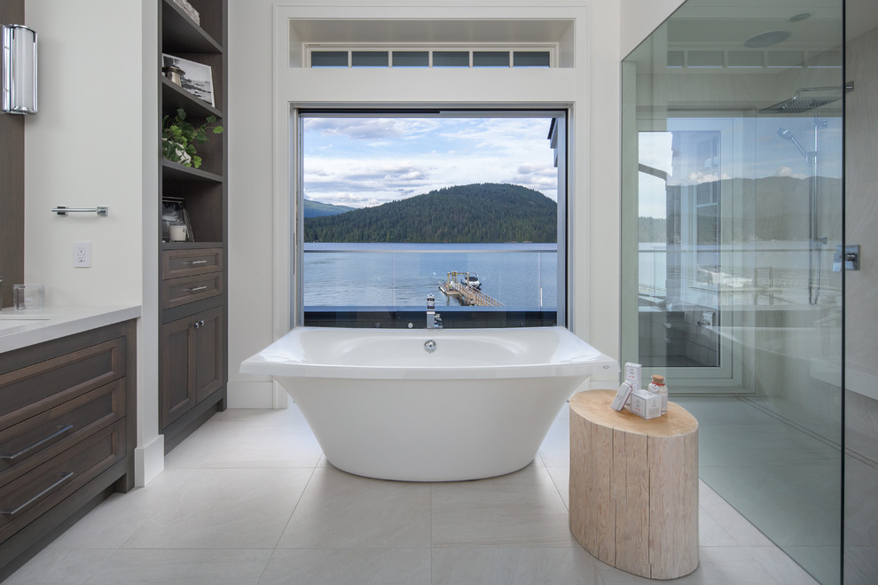 Beach style gray floor freestanding bathtub photo in Vancouver with recessed-panel cabinets, dark wood cabinets, white walls, an undermount sink and gray countertops