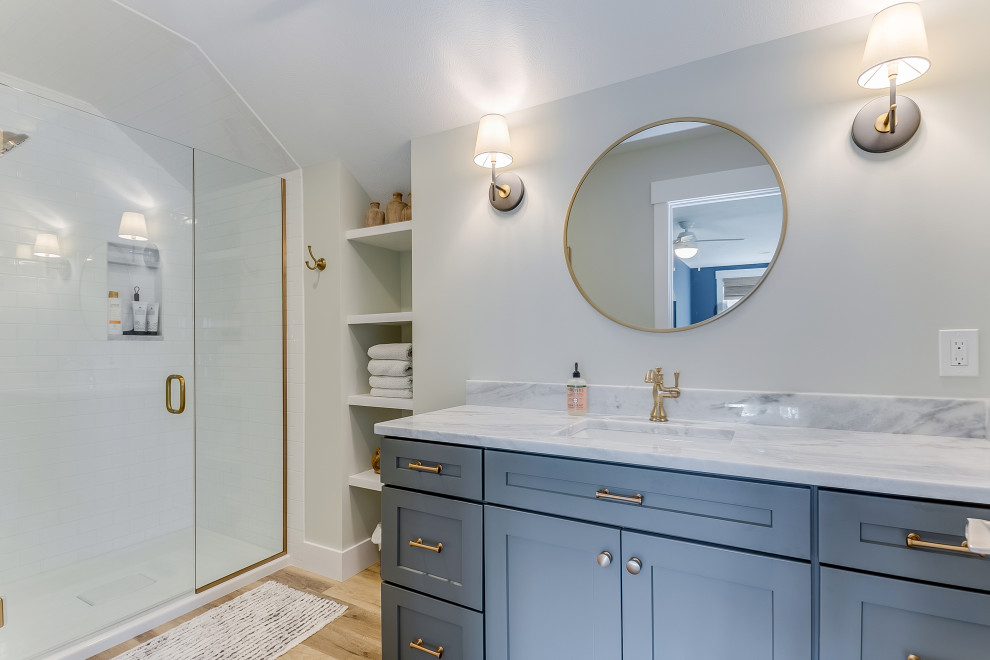 Bild på ett vintage grå grått badrum med dusch, med skåp i shakerstil, grå skåp, en dusch i en alkov, vit kakel, vita väggar, mellanmörkt trägolv, ett undermonterad handfat, marmorbänkskiva, brunt golv och dusch med skjutdörr