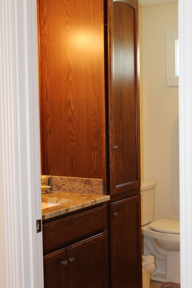 Пример оригинального дизайна: ванная комната среднего размера в стиле кантри с фасадами в стиле шейкер, темными деревянными фасадами, душем в нише, раздельным унитазом, бежевой плиткой, плиткой из травертина, бежевыми стенами, полом из травертина, врезной раковиной, столешницей из гранита, бежевым полом, душем с распашными дверями и разноцветной столешницей