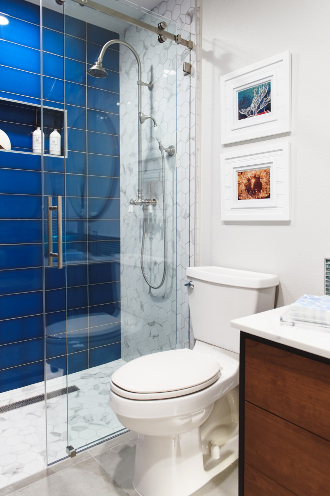 Свежая идея для дизайна: ванная комната среднего размера в морском стиле с фасадами островного типа, фасадами цвета дерева среднего тона, душем без бортиков, унитазом-моноблоком, синей плиткой, плиткой мозаикой, белыми стенами, полом из керамогранита, душевой кабиной, настольной раковиной, мраморной столешницей, бежевым полом, душем с раздвижными дверями, белой столешницей, нишей, тумбой под одну раковину и напольной тумбой - отличное фото интерьера