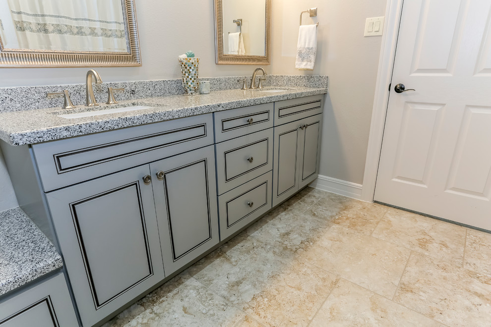 Example of a mid-sized beach style master beige tile and porcelain tile limestone floor bathroom design in Houston with raised-panel cabinets, gray cabinets, gray walls, quartz countertops, a two-piece toilet and an undermount sink