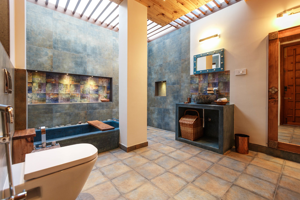 Diseño de cuarto de baño principal asiático con armarios abiertos, bañera esquinera, sanitario de pared, baldosas y/o azulejos marrones, paredes multicolor, lavabo sobreencimera, encimera de cemento y suelo beige