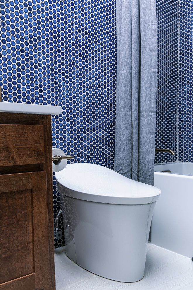 シカゴにあるお手頃価格の中くらいなトランジショナルスタイルのおしゃれなバスルーム (浴槽なし) (レイズドパネル扉のキャビネット、茶色いキャビネット、ダブルシャワー、一体型トイレ	、青いタイル、セメントタイル、青い壁、淡色無垢フローリング、オーバーカウンターシンク、珪岩の洗面台、白い床、シャワーカーテン、白い洗面カウンター) の写真