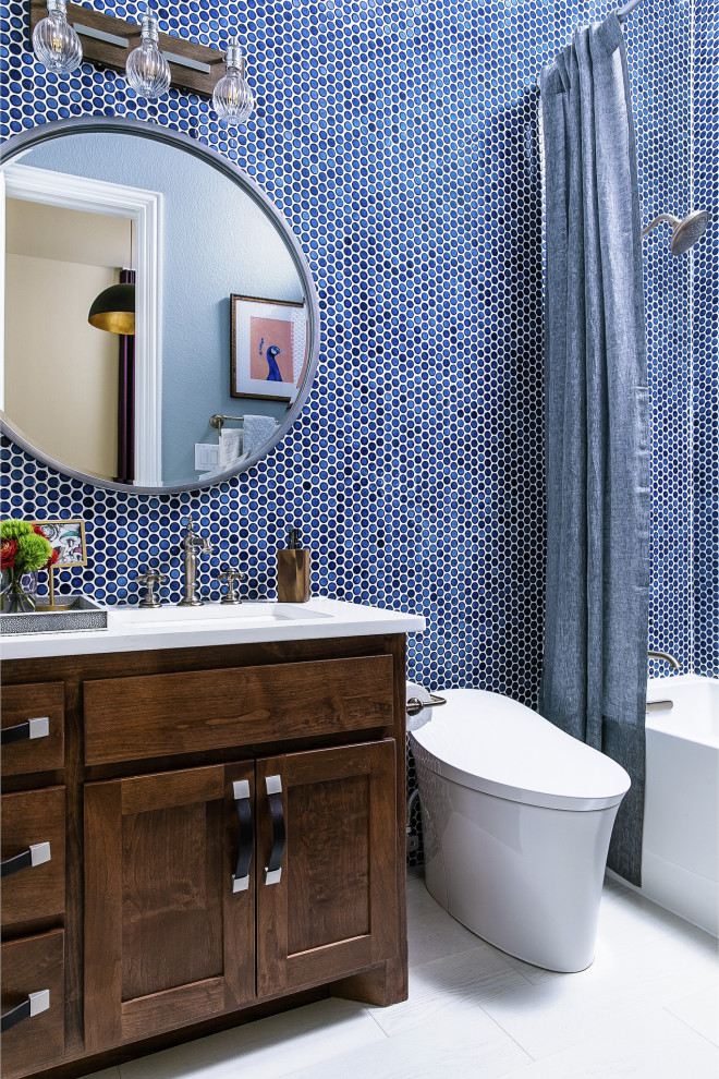 シカゴにあるお手頃価格の中くらいなトランジショナルスタイルのおしゃれなバスルーム (浴槽なし) (茶色いキャビネット、ダブルシャワー、一体型トイレ	、青いタイル、セメントタイル、青い壁、淡色無垢フローリング、オーバーカウンターシンク、珪岩の洗面台、白い床、シャワーカーテン、白い洗面カウンター、シェーカースタイル扉のキャビネット) の写真