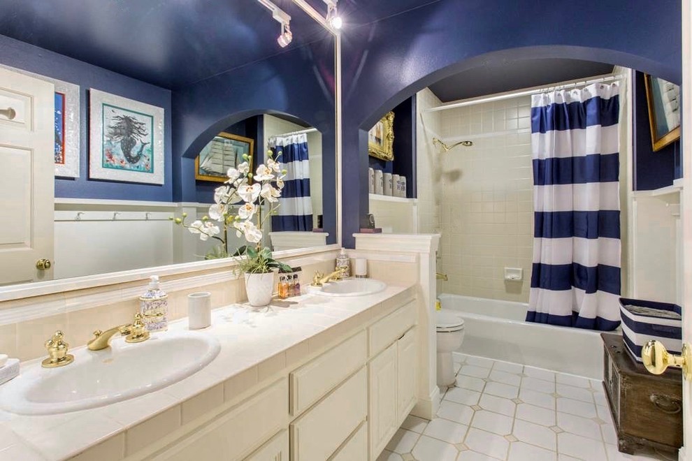 Modelo de cuarto de baño infantil contemporáneo de tamaño medio con armarios estilo shaker, puertas de armario blancas, bañera encastrada, paredes azules, suelo de baldosas de porcelana, lavabo encastrado, encimera de azulejos, suelo gris, ducha con cortina y encimeras beige