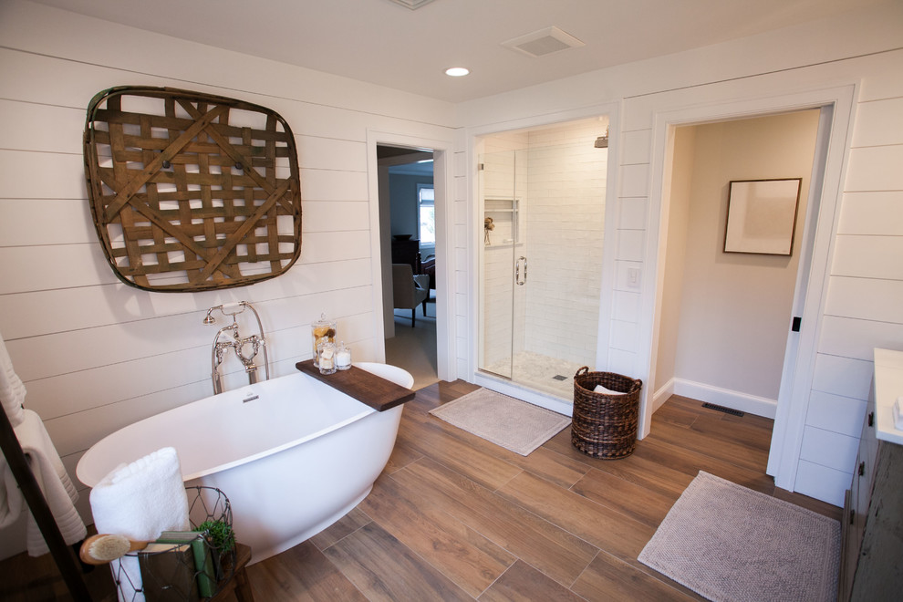 Photo of a large classic ensuite bathroom in Philadelphia with freestanding cabinets, distressed cabinets, a freestanding bath, an alcove shower, a two-piece toilet, white tiles, ceramic tiles, white walls, porcelain flooring, a submerged sink, glass worktops, brown floors and a hinged door.