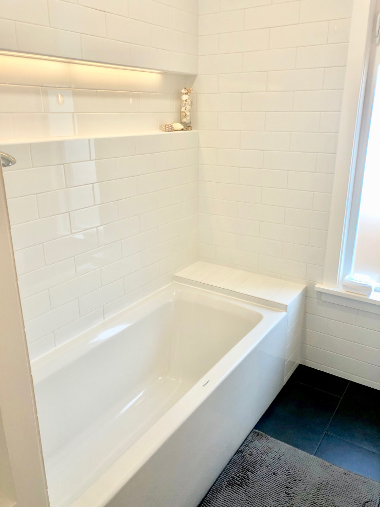 На фото: ванная комната среднего размера в стиле модернизм с плоскими фасадами, белыми фасадами, ванной в нише, душем над ванной, унитазом-моноблоком, белой плиткой, плиткой кабанчик, белыми стенами, полом из керамогранита, душевой кабиной, монолитной раковиной, черным полом и шторкой для ванной